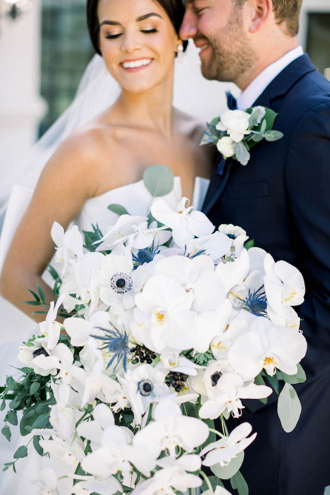 The bride and groom smiling with their faces close, the bride is holding a white bouquet. 