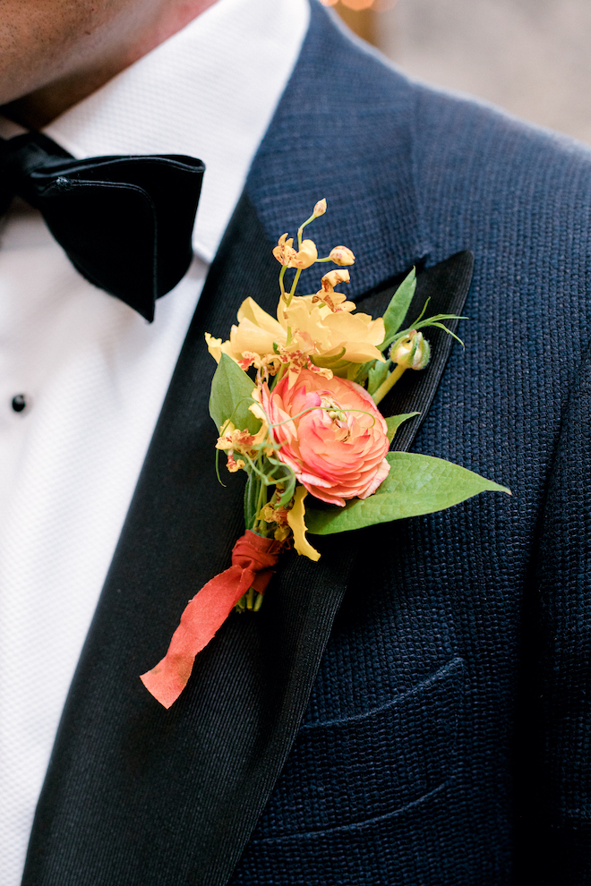 Florals pinned to the groom's jacket for the colorful spring wedding.