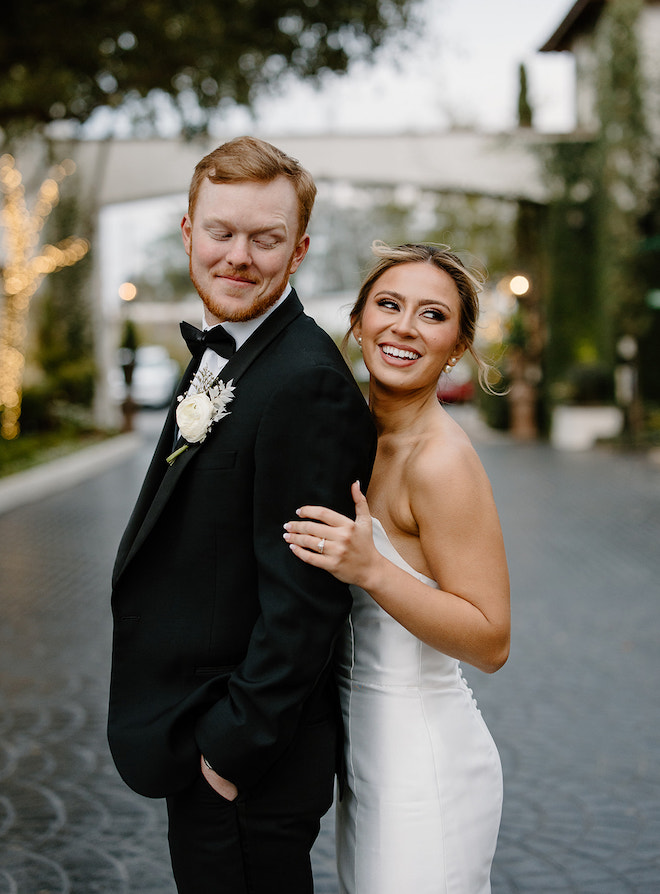 Groom and bride smile outside of their wedding venue, The Bell Tower on 34th.
