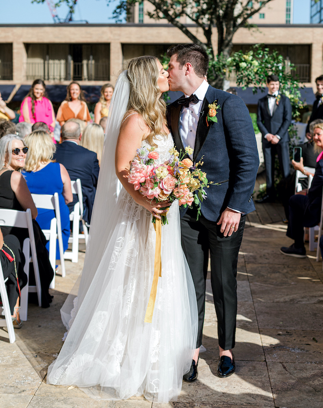 The bride and groom kissing as they leave their wedding ceremony. 