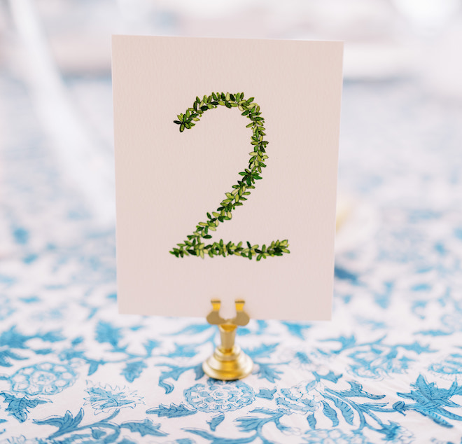 The hand-printed table number "2" painted in green leaves.
