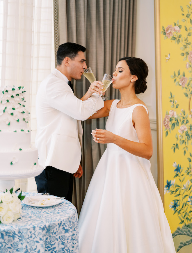 The bride and groom taking a sip of champagne at their chinoiserie inspired wedding reception.