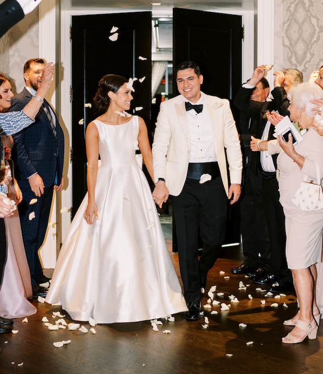 The bride and groom entering the reception venue with white petals being thrown.
