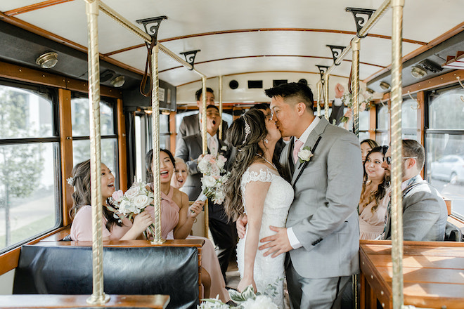 The bride and groom kissing on the trolley as they make their way to the wedding ceremony. 