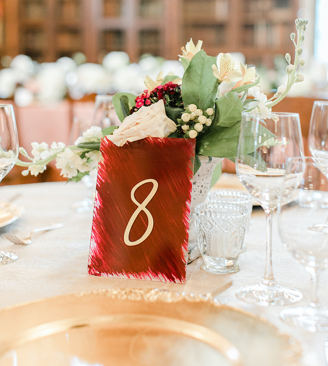 A red table number "8" with florals and gold plates. 