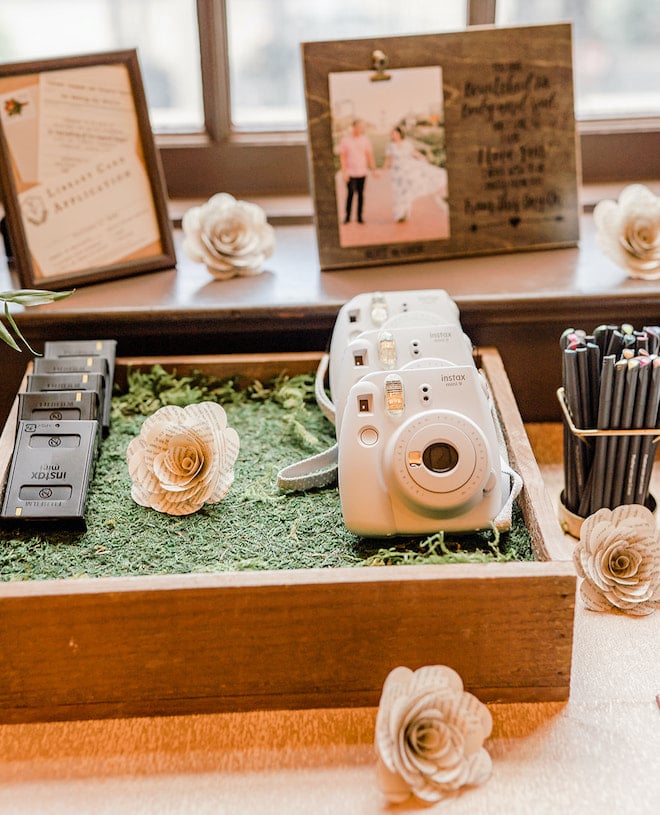Polaroid cameras for the guests to take photos surrounded by flowers made out of book pages.