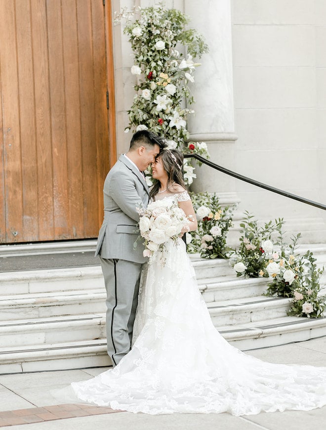 The bride and groom smiling at each other in front of the library steps. 