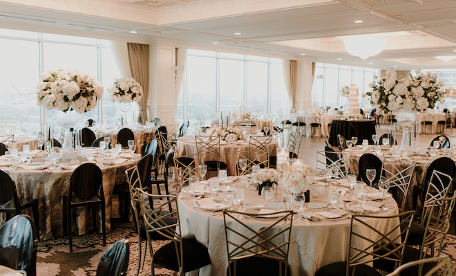Downtown wedding venue, The Petroleum Club of Houston, decorated for a wedding reception with round banquet tables, gold linens and tall floral centerpieces. 