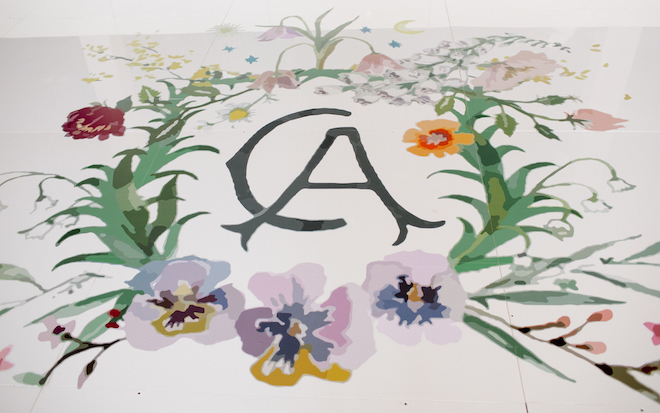 A crest with the couple's initials "C and A" on the dance floor surrounded by flowers.