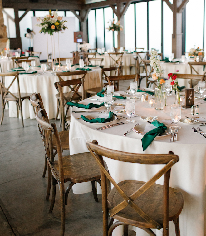 The indoor reception tables with white table cloths and green napkins.