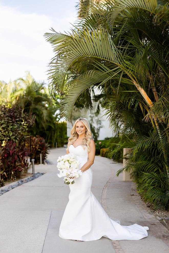 The bride posing in her gown from Belle Ame Bridal and her white bouquet. 