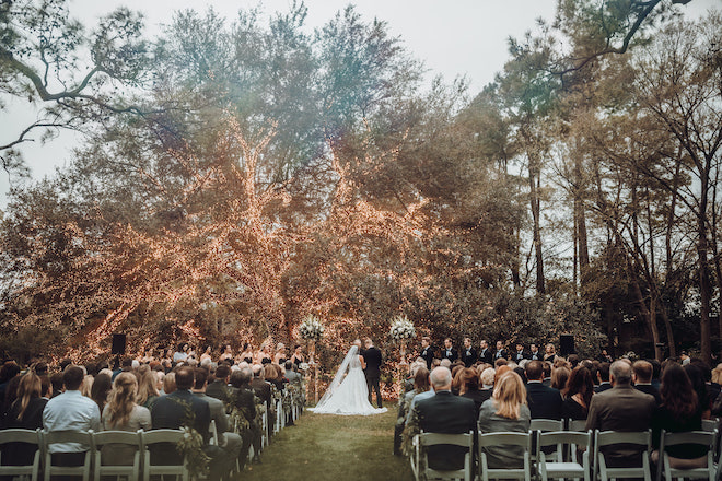 An outdoor wedding ceremony under the lit up oak tree at The Houstonian.