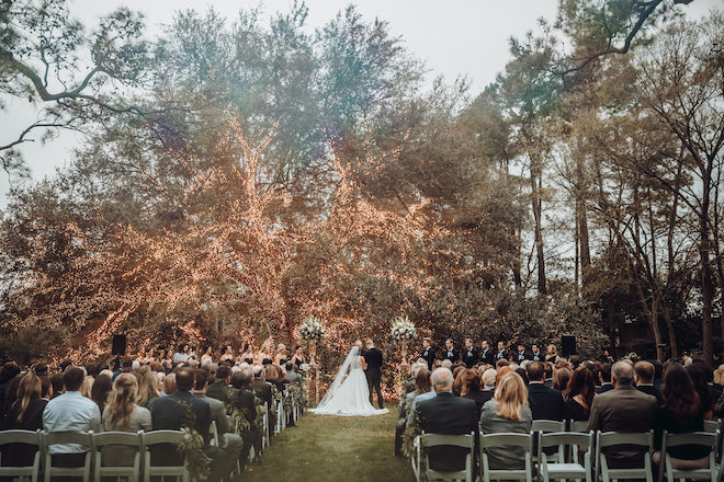 An outdoor wedding ceremony under the lit up oak tree at The Houstonian.