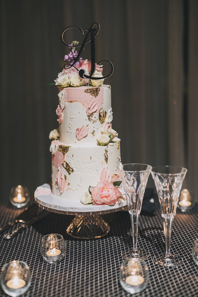 Two-tiered pink and gold wedding cake.