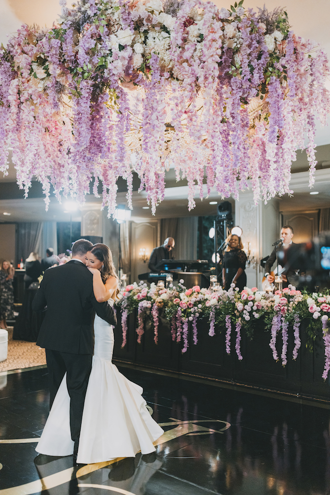 The bride and groom dancing under the purple blooms at their wedding in the museum district.