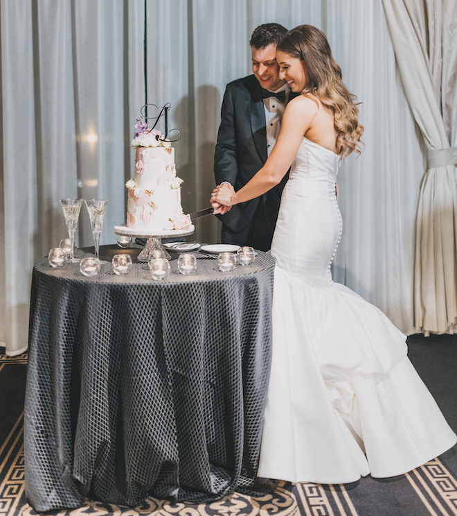 The bride and groom cutting the pink and gold wedding cake in the ballroom.