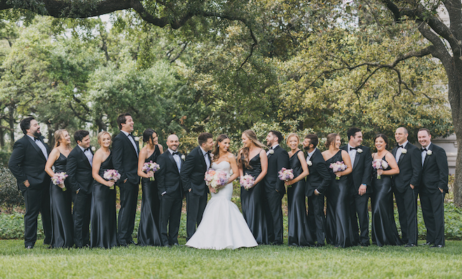 The entire wedding party in black with the bride in her glamorous white gown in the center.
