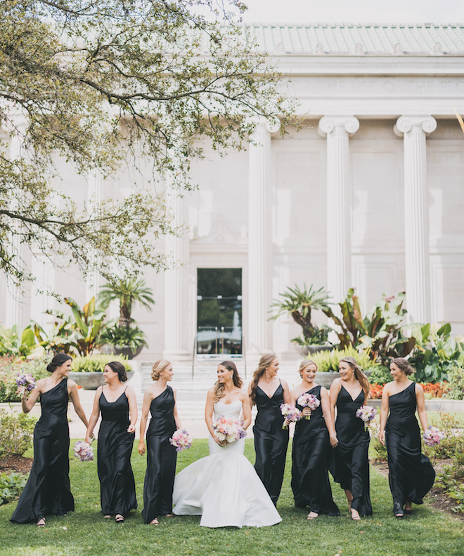 The bride and bridesmaids walking with pink and purple bouquets.