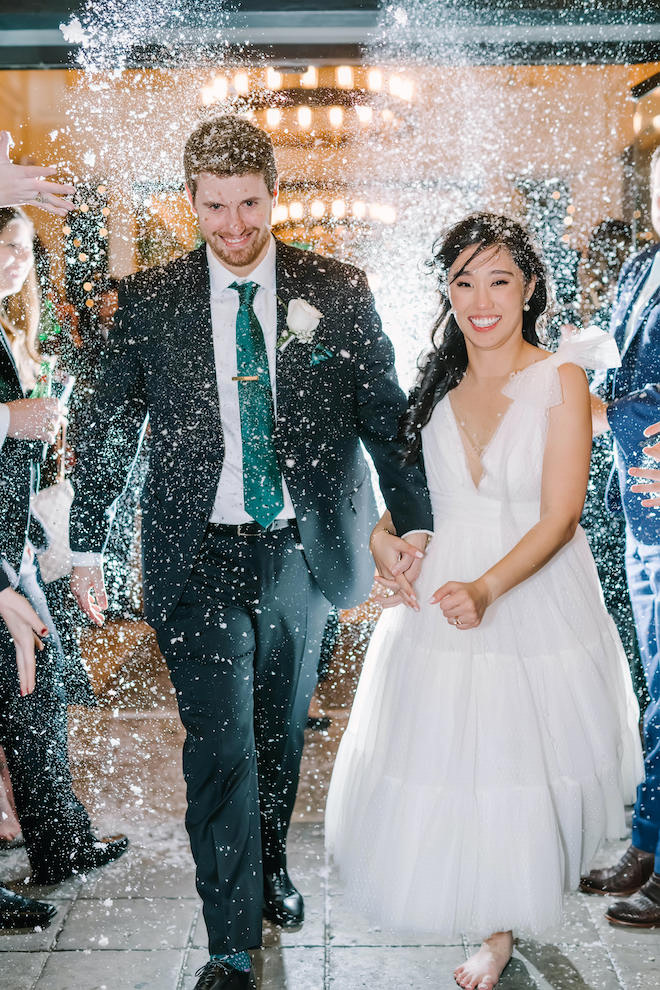 The bride and groom holding hands during their send off from the downtown boutique hotel.