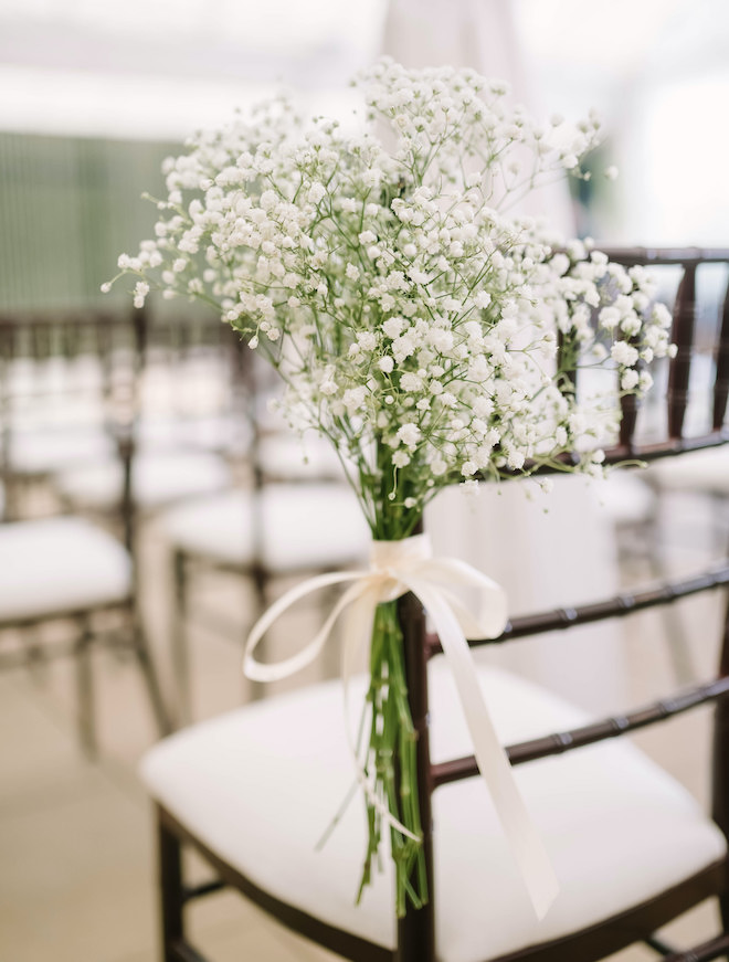 A bouquet of baby's breath tied to the seats at the ceremony.