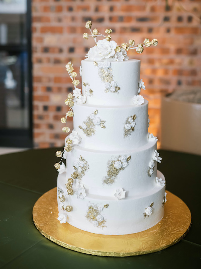 Four-tiered white and gold wedding cake.