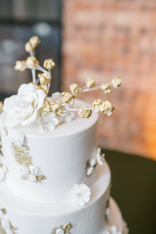White wedding cake garnished in gold decor.