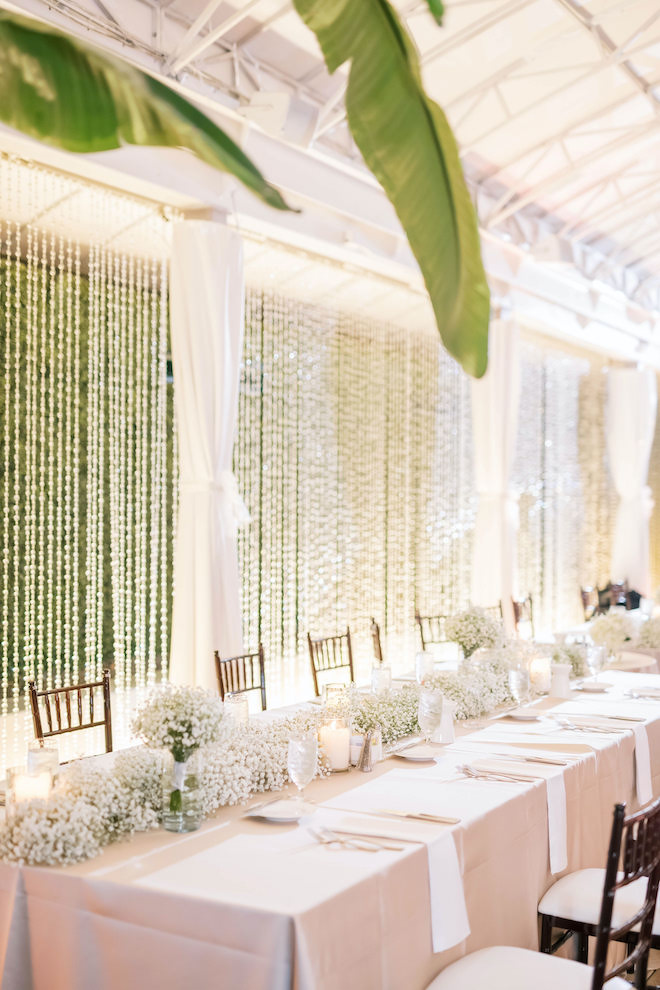 A long reception table covered in baby's breath at the white and forest green wedding.