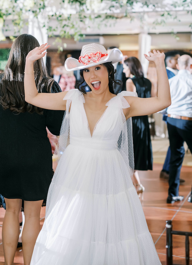 The bride dancing with a sparkly cowboy hat on.
