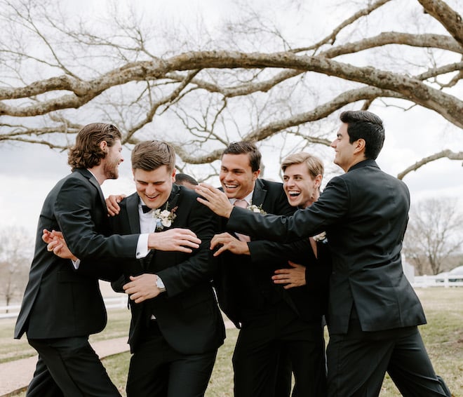The groom and his groomsmen huddled together, laughing.