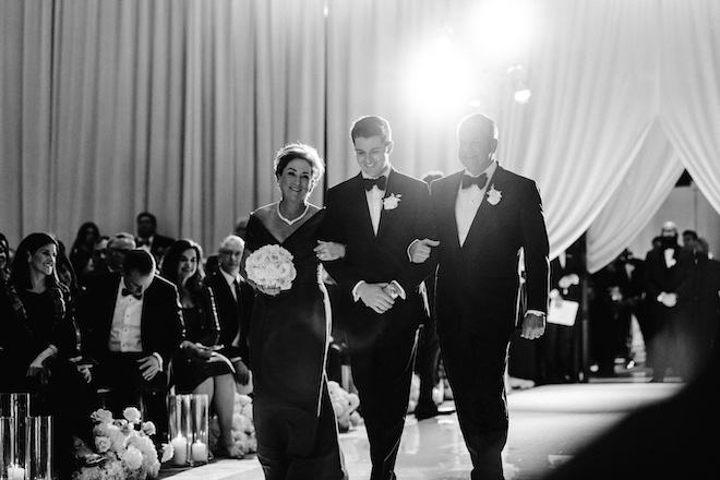 The groom's parents walking the groom down the aisle.