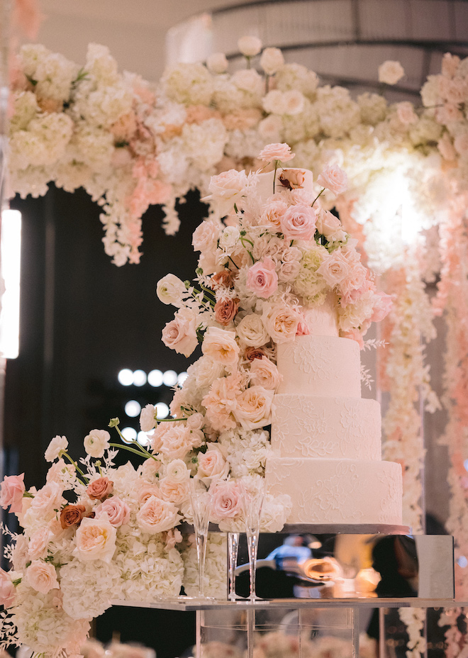 A grand white wedding cake covered in delicate roses.