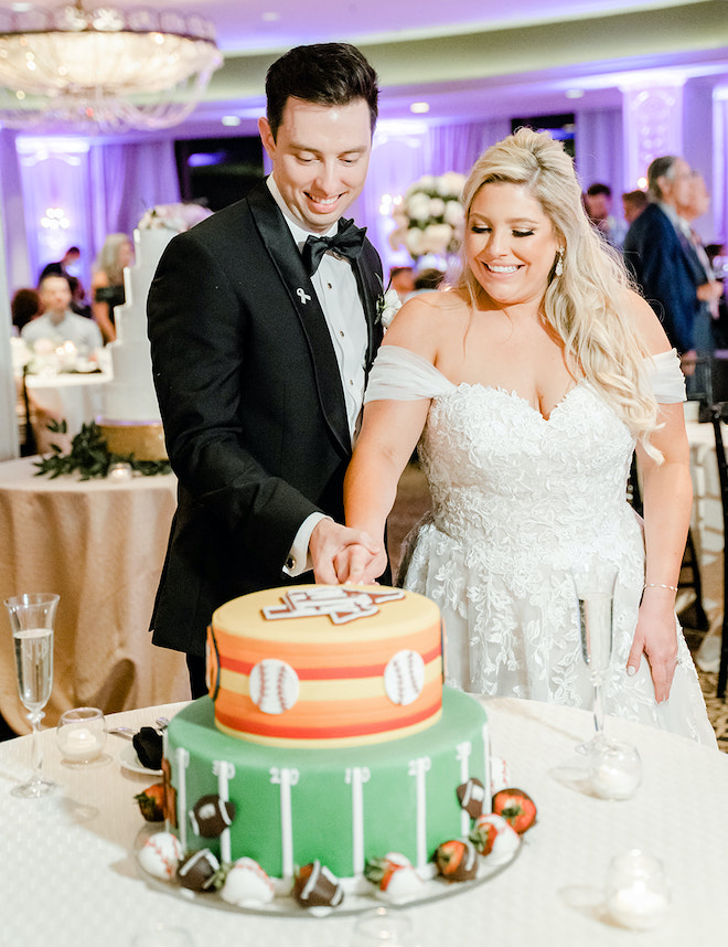 The bride and groom cut into a two tiered Astros Baseball and Texas A&M themed cake created by Susie's Cakes at their ballroom reception in Houston, TX.