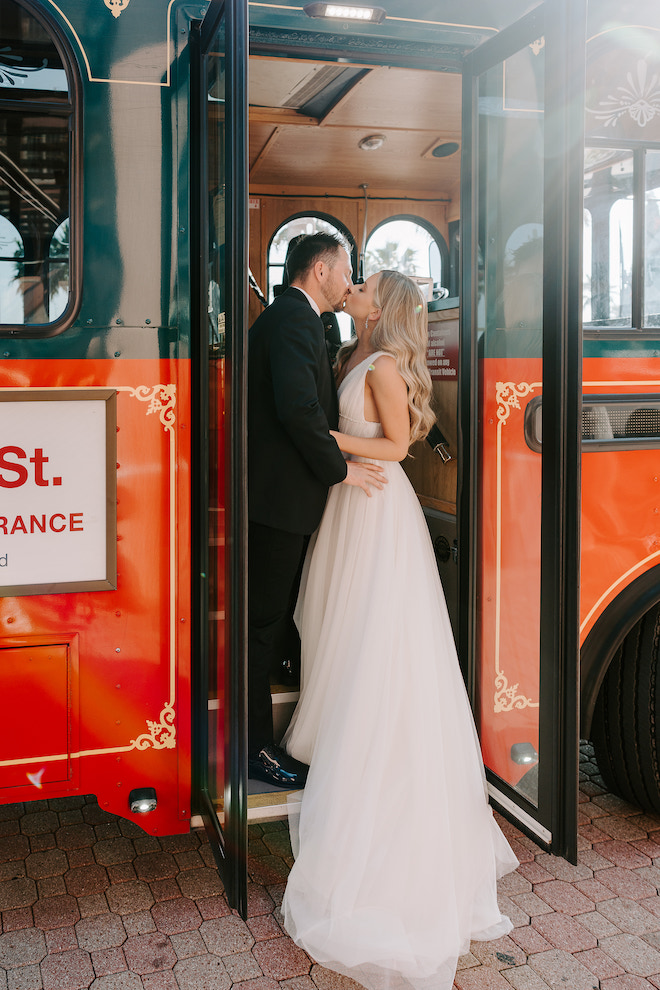 The bride and groom kissing in the door of the Galveston Island Trolley.