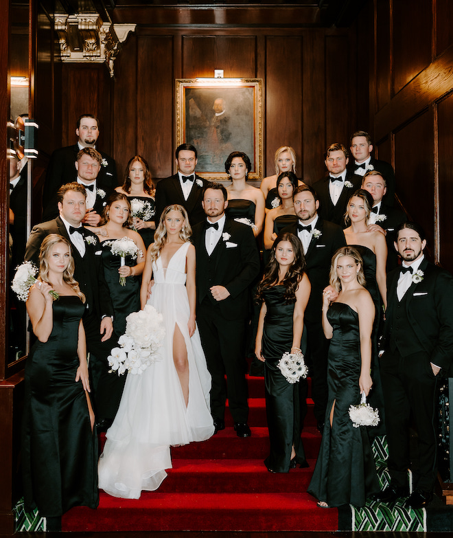 The couple and their wedding party posing on the red steps at Grand Galvez for their winter wedding in Galveston, Texas.