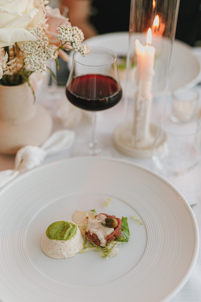 A glass of wine and a plate of food at the reception.