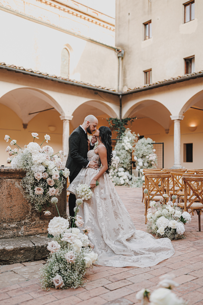 The bride and groom about to kiss after their ceremony, covered in blooms and baby's breath.