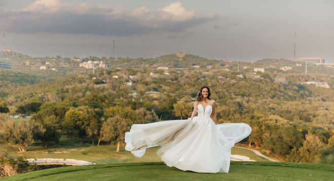 The bride smiling as her dress flows in the wind overlooking the Austin hill country.