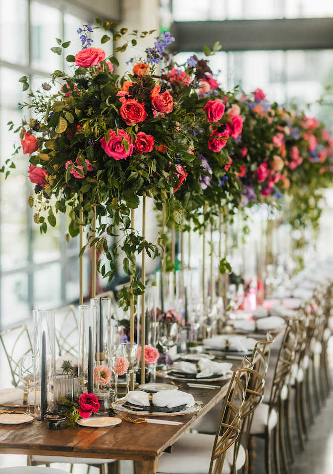Floral centerpieces with greenery, red and orange roses.