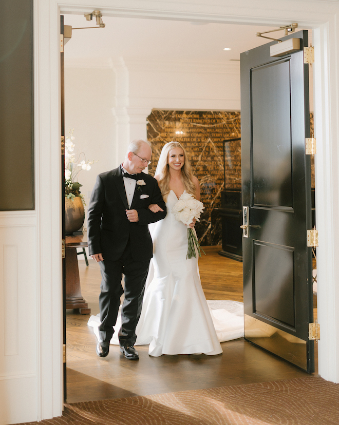 The bride and her dad walking down the aisle at their sophisticated ceremony at the Petroleum Club of Houston.