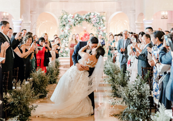 The bride and groom kissing as they walk back down the aisle.