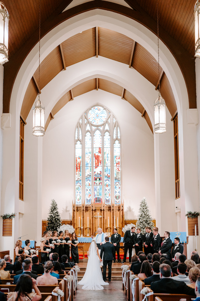 The couple holding hands in the aisle of the church at their wedding ceremony.