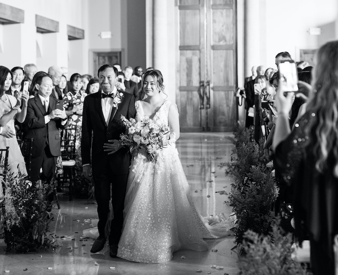 The bride walking down the aisle with her father.