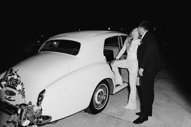 The bride and groom kissing as they get into a vintage car.