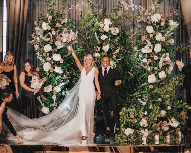 The bride and groom smiling as the bride holds her bouquet in the air after their wedding ceremony.