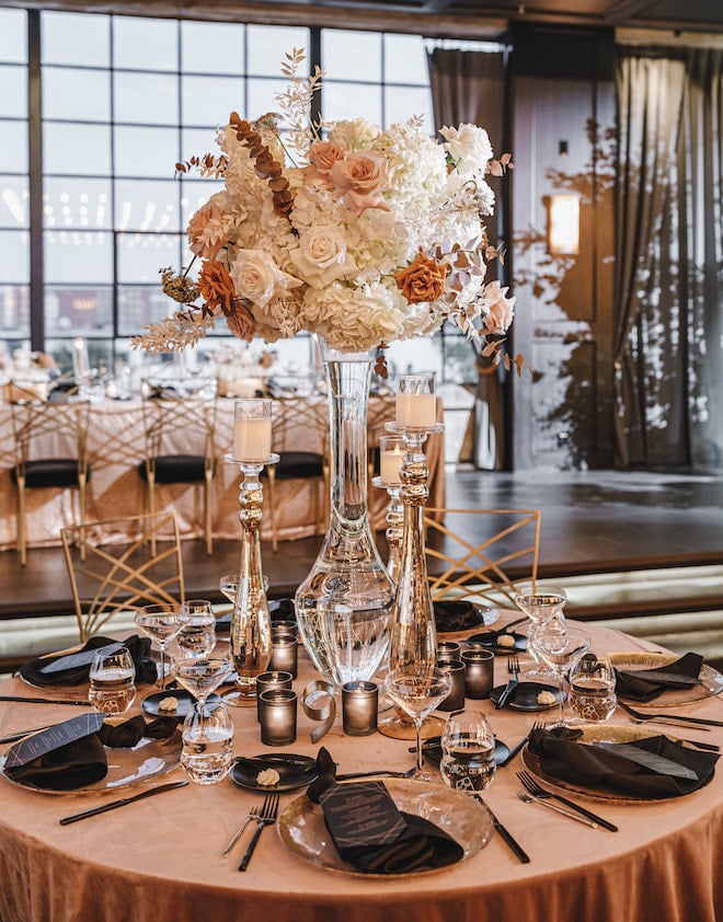 White, champagne and blush floral centerpiece with beige and black linens.