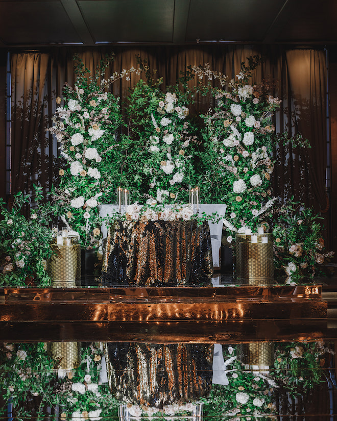 Blush and champagne flowers with greenery above a gold sequin table.