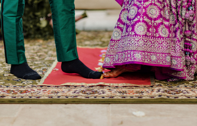 The bride and groom are barefoot as they participate in a traditional Hindu wedding ceremony ritual. 