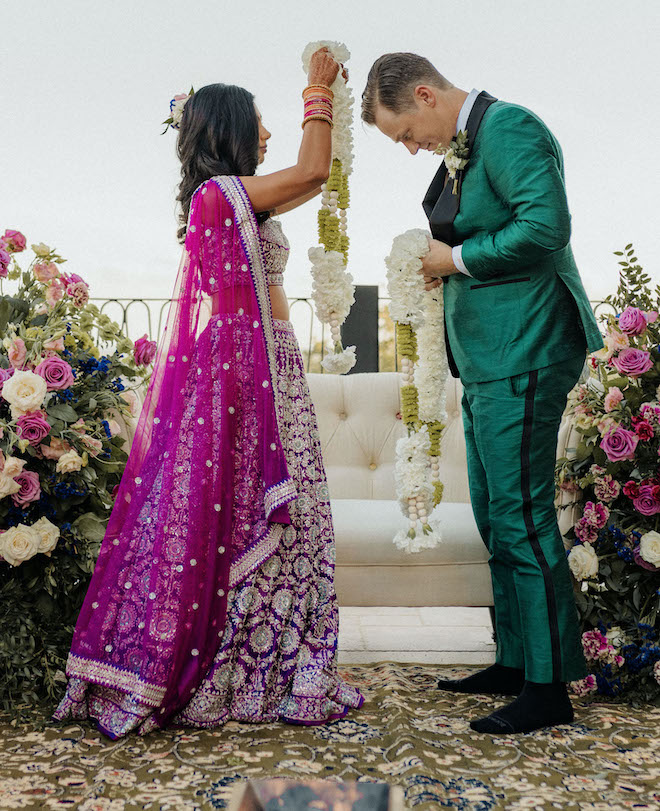 The bride and groom place white floral Varmala around each others neck at their Hindu wedding ceremony.