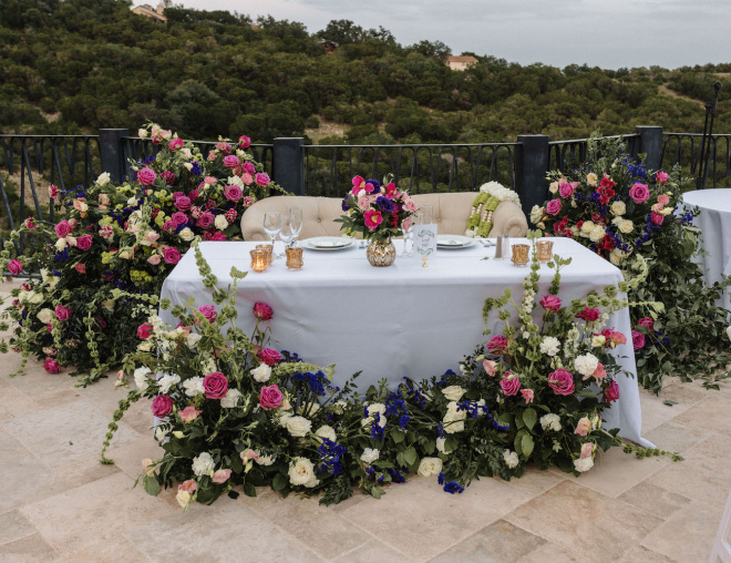 Mauve and white color floral installations decorate the bride and grooms table at the outdoor wedding reception in Austin, Texas. 