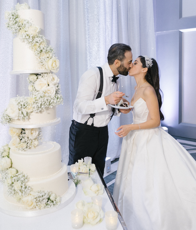 Newly married couple kiss aside a Five tiered wedding cake on their wedding day at Omni Houston Hotel. 